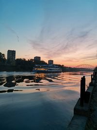 Scenic view of sea by buildings against sky during sunset