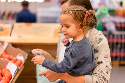 Woman holding girl at supermarket