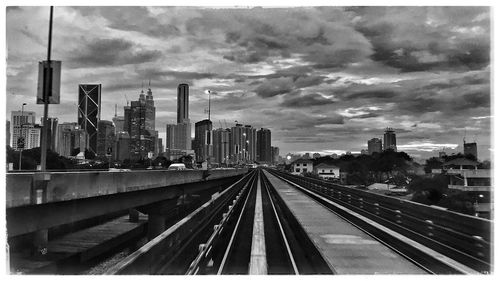 Railroad tracks in city against storm clouds