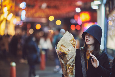 Woman wearing hat on city street at night