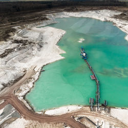 Aerial view of the long boom of a suction excavator in a quartz quarry for the excavation of sand.