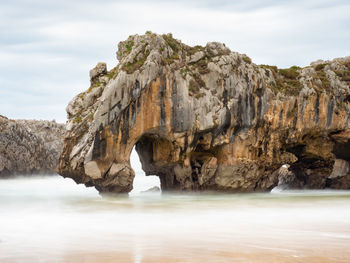 Rock formation in sea against sky