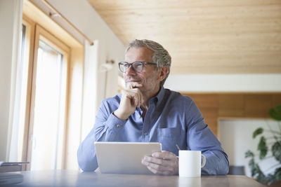 Mature man using digital tablet on table at home