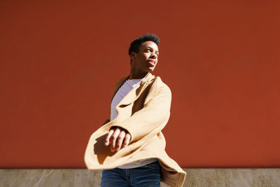 Young man looking away against wall