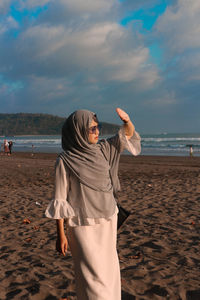 Woman standing at beach against sky