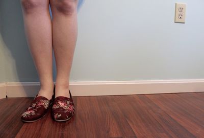 Low section of woman standing on hardwood floor at home