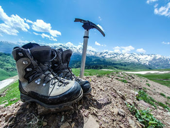 Close-up of shoes on field against sky