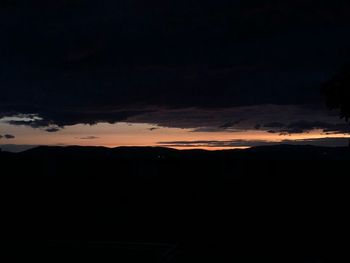 Silhouette landscape against dramatic sky during sunset