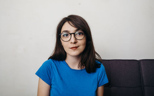 Portrait of beautiful young woman against wall