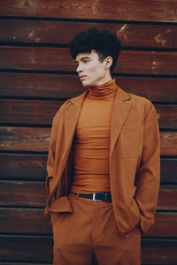 Portrait of young man standing against wall