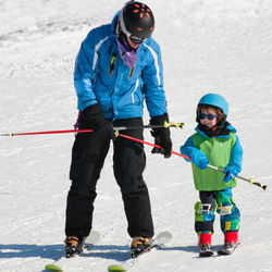 Father and son skiing on snow covered field during winter