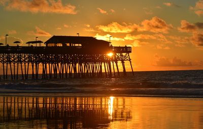 Pier over sea against orange sky