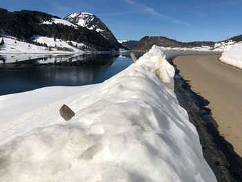 Scenic view of lake by snowcapped mountain against sky