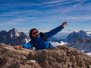 Portrait of smiling man standing on rock against snowcapped mountains