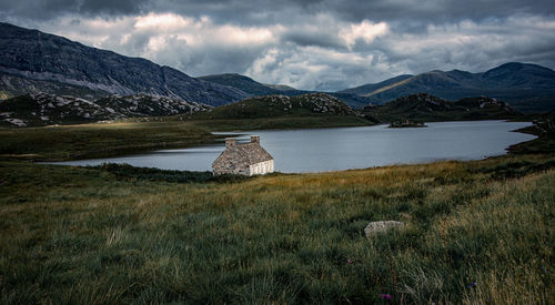 A remote highland bothy sitting on the banks of loch stack.with mountain tops of arkle in background