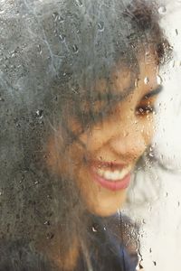 Portrait of woman with wet window in rainy season