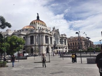 Tourists in front of building against sky