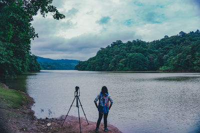 People photographing lake against sky