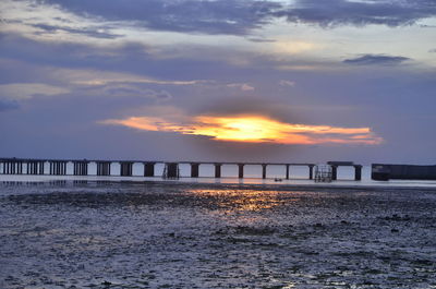 Pier over sea against sky during sunset