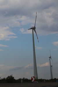 Low angle view of windmill on field against sky