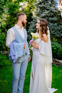 Full length of couple standing against trees