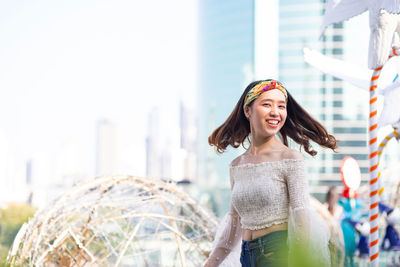 Smiling young woman standing against city in background