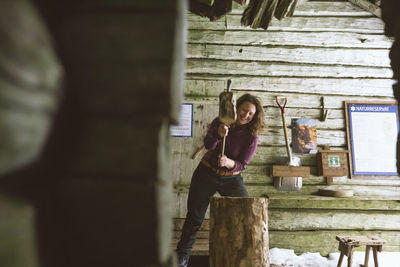 Woman chopping wood in shed