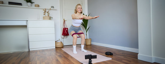 Full length of young woman exercising at home