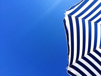 Low angle view of beach umbrella against clear blue sky