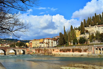 Arch bridge over river against buildings in city