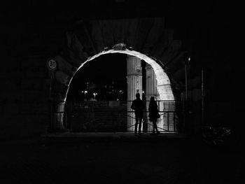 Silhouette people standing at illuminated archway