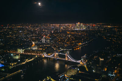 Illuminated tower bridge over thames river in city against sky at night