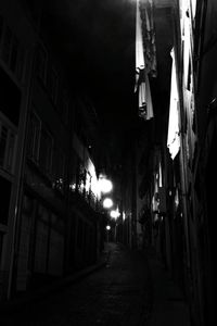 Empty alley amidst buildings in city at night