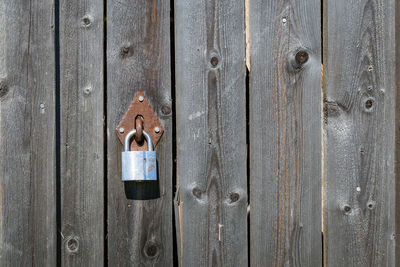 Padlock hanging from closed wooden door