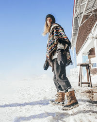 Man wearing poncho standing on snownext to mountain hut