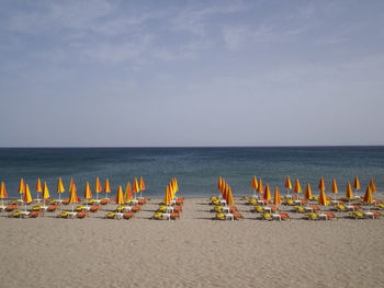 Deck chairs on beach against sky