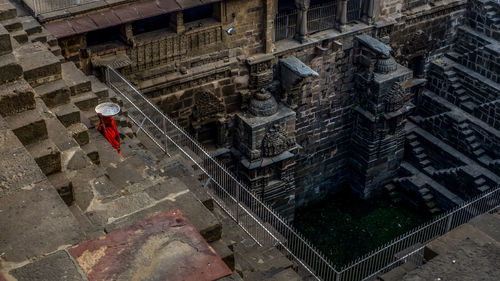 High angle view of woman carrying container while walking at historic building
