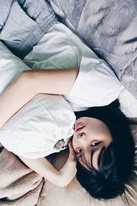 High angle portrait of woman lying on bed