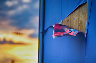 Close-up of torn paper on window during sunset