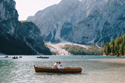 People on boat on lake against mountains