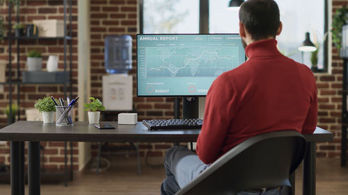 Rear view of businessman using desktop pc at office