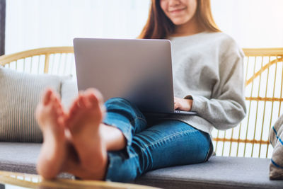 Midsection of woman using laptop at home