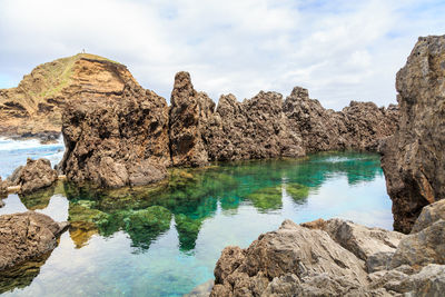 Rocks by sea against sky