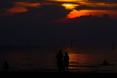 Silhouette woman walking at beach against sky during sunset