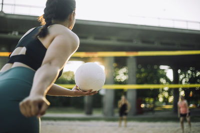 Woman preparing for serve while playing volleyball with friends