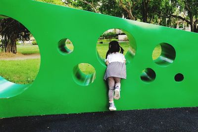 Rear view of girl leaning on wall in playground