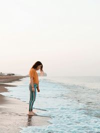 Full length of man standing on beach against clear sky