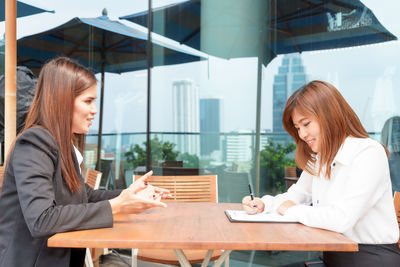 Side view of young woman sitting on table