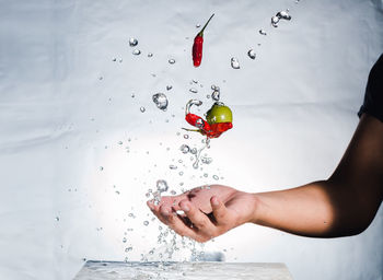 Close-up of hand splashing water with red chili peppers and olive