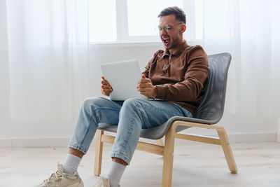 Young woman using laptop while sitting on sofa at home